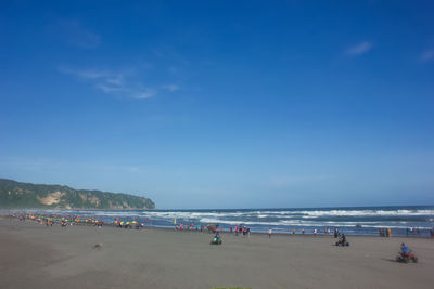 People on beach against blue sky