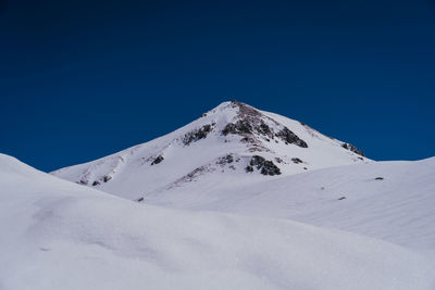 Scenic view of snowcapped mountains against clear blue sky