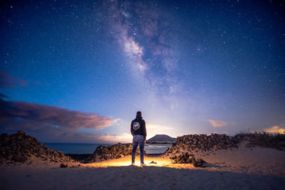 Rear view of man standing against sky at night