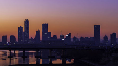 Modern buildings in city against sky during sunset