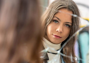 Portrait of beautiful young woman face reflecting in broken mirror