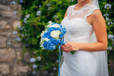 Midsection of woman holding white flower