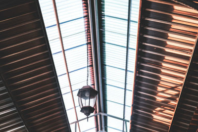 Low angle view of illuminated light fixture on ceiling of building