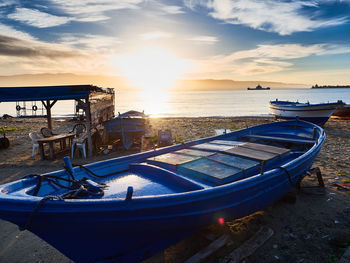 Boats moored on sea against sky during sunset