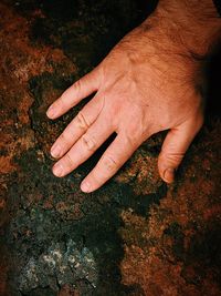 Cropped hand of man touching rusty metal