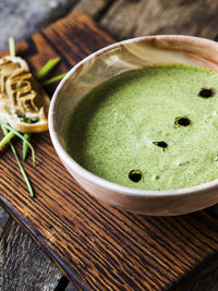 Close-up of spinach soup with bread served on cutting board