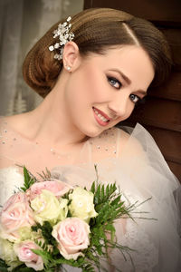 Close-up of beautiful bride holding bouquet while standing at home