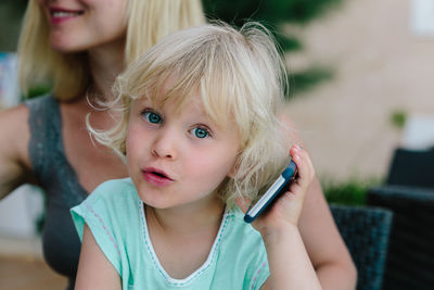 Close-up of cute girl holding mobile phone at home