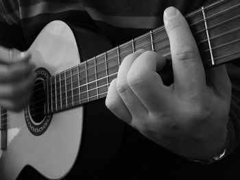 Midsection of musician playing acoustic guitar