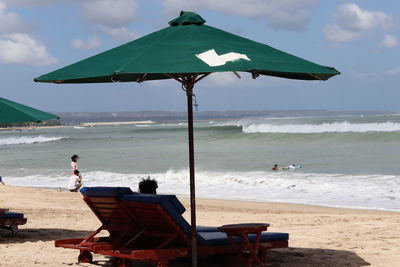 Deck chairs on beach against sky