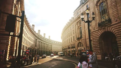 People on city street amidst buildings against sky