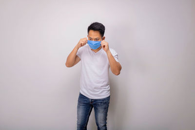 Full length of young man standing against white background