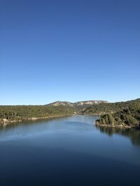 Scenic view of lake against clear blue sky