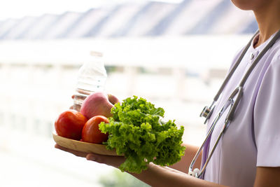 Midsection of woman holding strawberry outdoors
