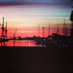 Silhouette boats moored at harbor against sky at sunset