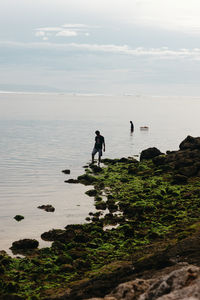 Rear view of man walking on beach against sky
