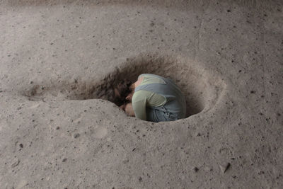 High angle view of girl sitting in hole
