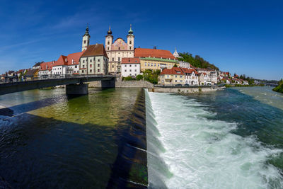 Buildings at waterfront against blue sky