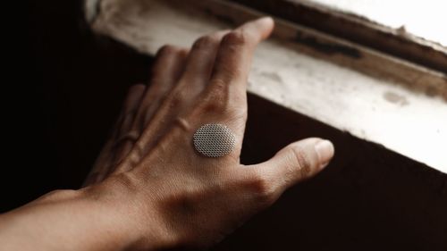 Cropped hand of person against a lit window