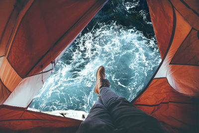 Low section of man in portaledge over sea