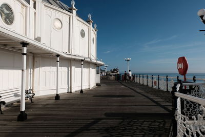 Low angle view of people walking on pier in sea