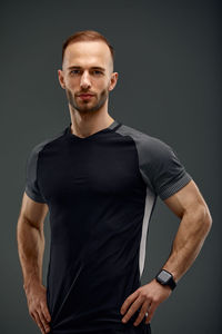 Portrait of young man standing against black background