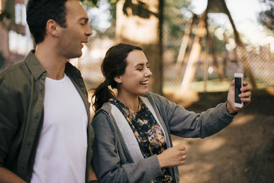 Young man photographing while using smart phone