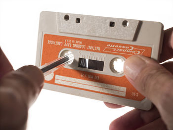 Close-up of hand holding guitar against white background