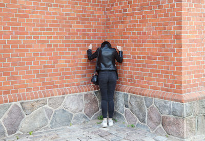 Full length of man standing against brick wall