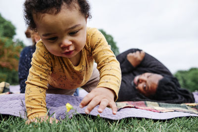 Boy touching flower in grass at park