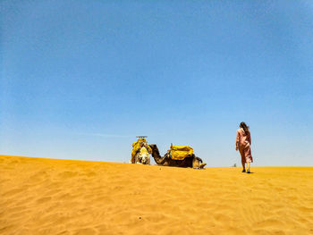 People on desert against clear sky