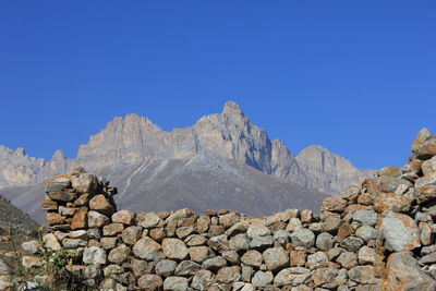 Stack of rocks on mountain against clear blue sky