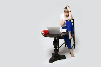 Portrait of young woman using mobile phone against white background