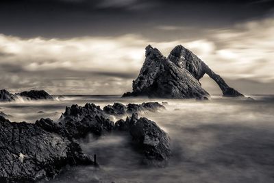 Scenic view of rocks in sea against sky