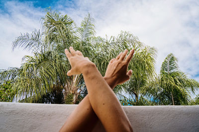 Woman hands crossed  against sky on a tropical background 