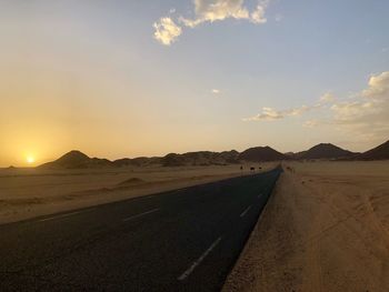 Road by land against sky during sunset