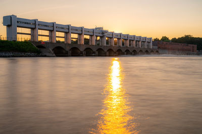 Arch bridge over river against sky during sunset