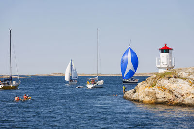 Sailboats and kayaks in a rocky archipelago by a lighthouse