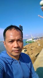 Portrait of man on beach against blue sky