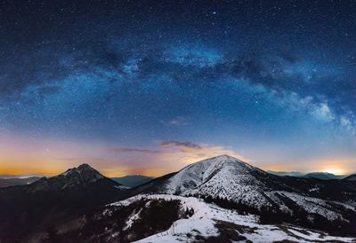 Scenic view of snowcapped mountains against sky at night