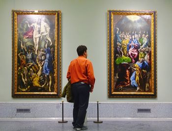 Rear view of man looking at statue in museum