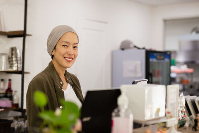 Woman restaurant owner standing at counter receiving orders.