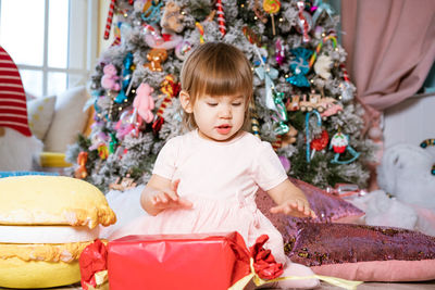 A little girl plays near the christmas tree