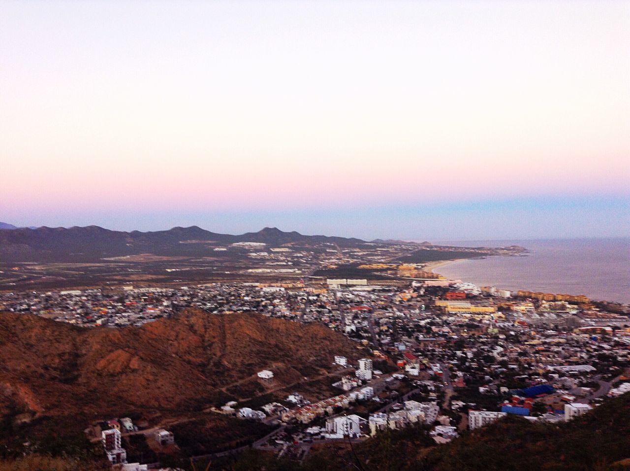 HIGH ANGLE VIEW OF CITYSCAPE AND SEA AGAINST SKY