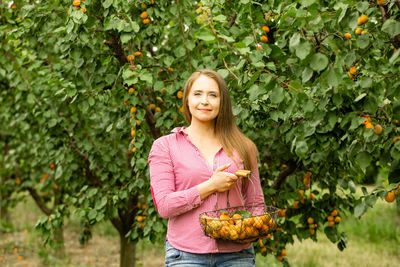 Portrait of smiling woman standing by plants