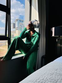Portrait of a young black woman  while sitting by the window witha doek on