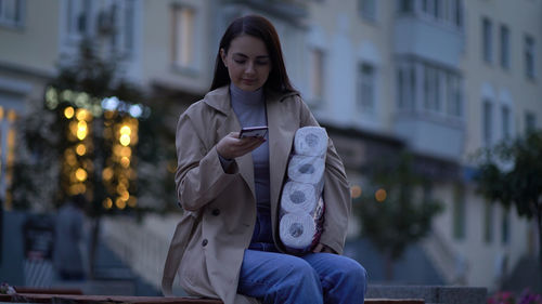 Full length of woman using mobile phone in city