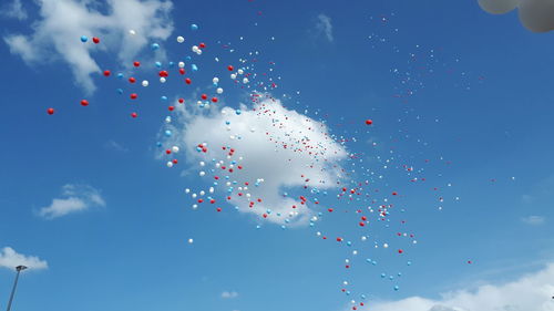 Low angle view of balloons flying against blue sky