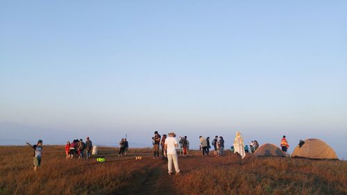 People on landscape against clear sky