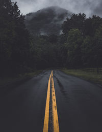 Empty road amidst trees against sky